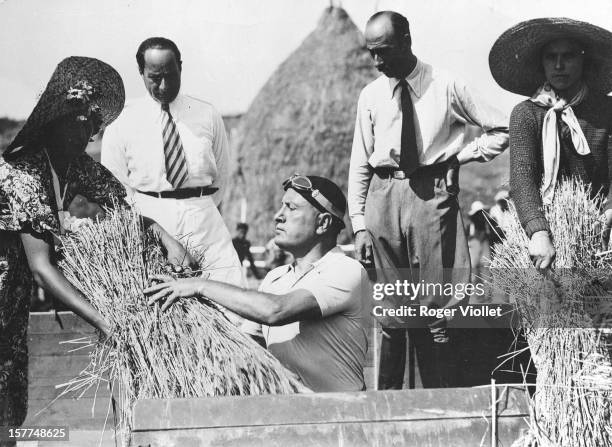 Italian statesman Benito Mussolini with farmers, taking part in the first threshing of the wheat in Littoria , a city created in the Pontine Marshes...