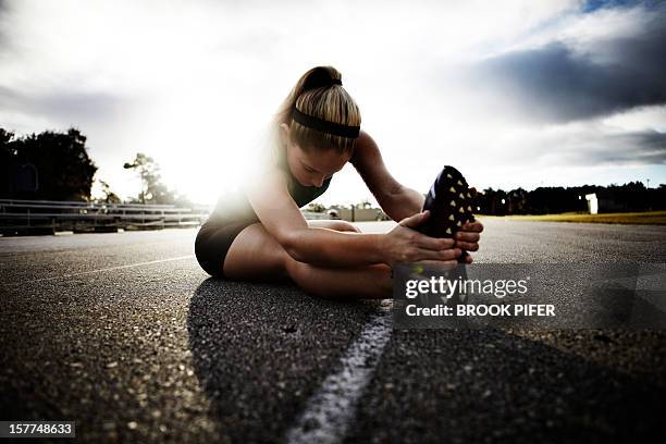 young woman athlete stretching on track - running track stock pictures, royalty-free photos & images
