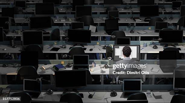 an office worker sits working in an empty office - working late stock-fotos und bilder