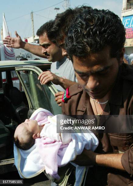 Medics in the port city of Saida carry a newborn baby evacuated with his mother, who was injured during the Israeli bombardment of their village...
