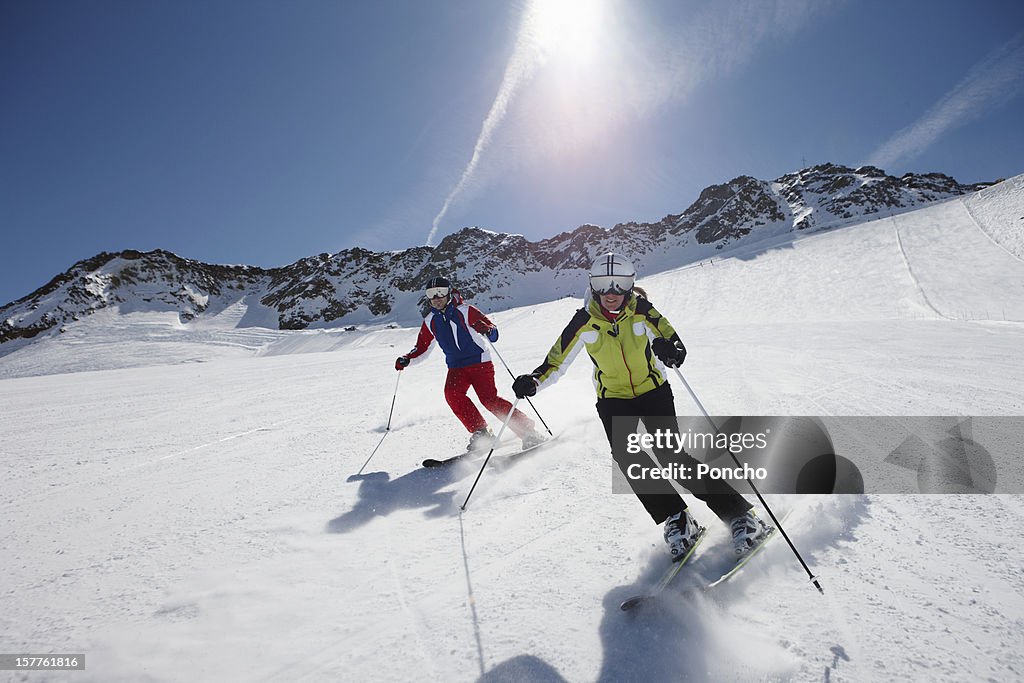 Couple skiing down a piste