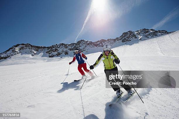couple skiing down a piste - skiing foto e immagini stock