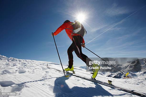 man ski touring up a mountain - esquíes de fondo fotografías e imágenes de stock