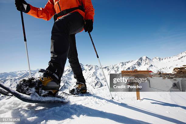 man snowshoeing at mountain top - スキーパンツ ストックフォトと画像