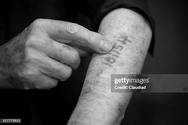 hombre viejo está mostrando su número él en ausschwitz - holocaust photos fotograf�ías e imágenes de stock