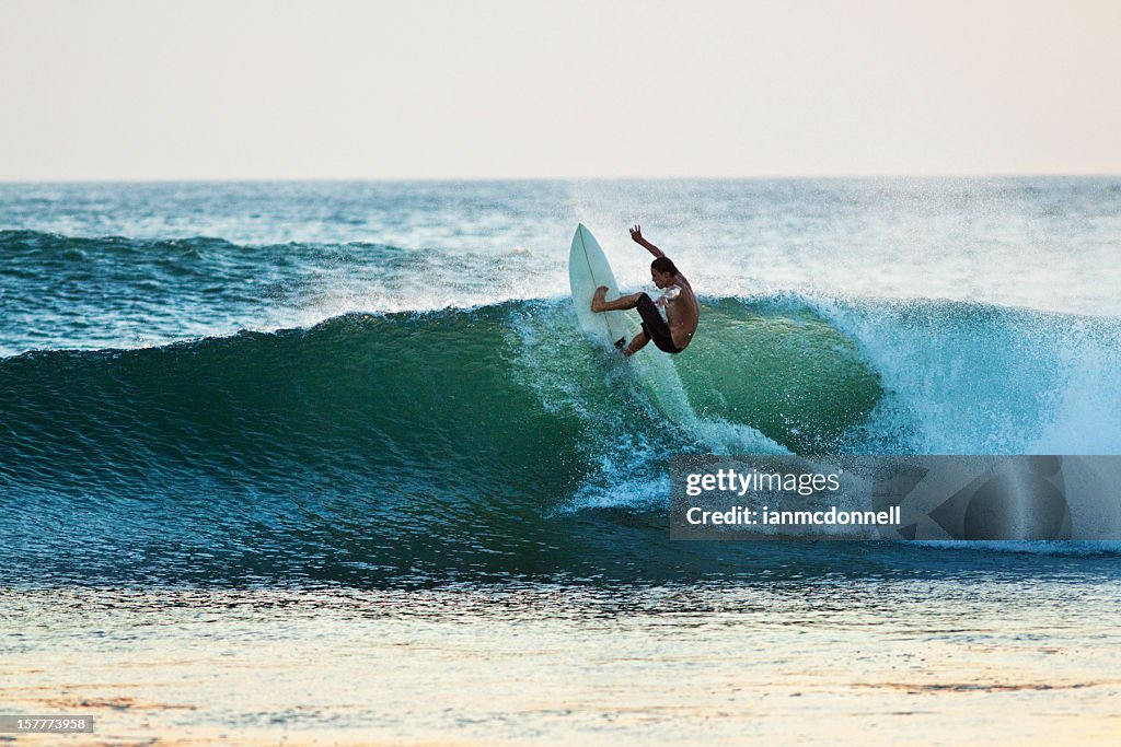 Surfer riding a wave off the top