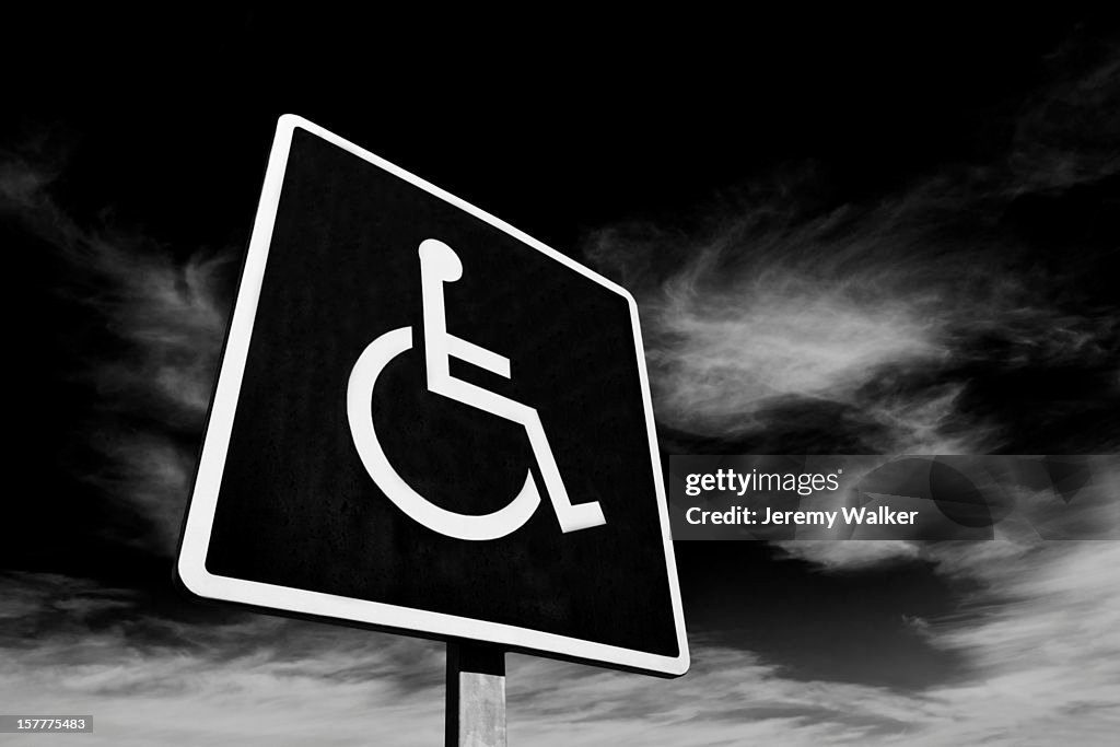 Disabled sign against dramatic dark sky