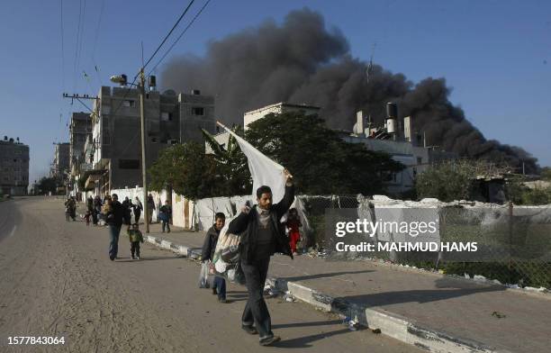 Palestinian man holds a white flag as he flees with other families the Zeitun district of Gaza City after Israeli strikes on January 12, 2009....