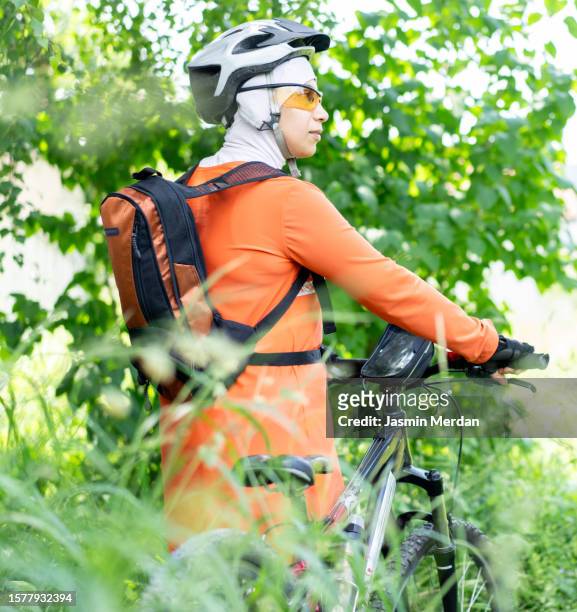 muslim woman riding bike in forest - veil isolated stock pictures, royalty-free photos & images