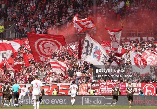 August 2023, Hamburg: Soccer: 2nd Bundesliga, Matchday 2, FC St. Pauli - Fortuna Düsseldorf, at Millerntor Stadium. Düsseldorf's fans set off...