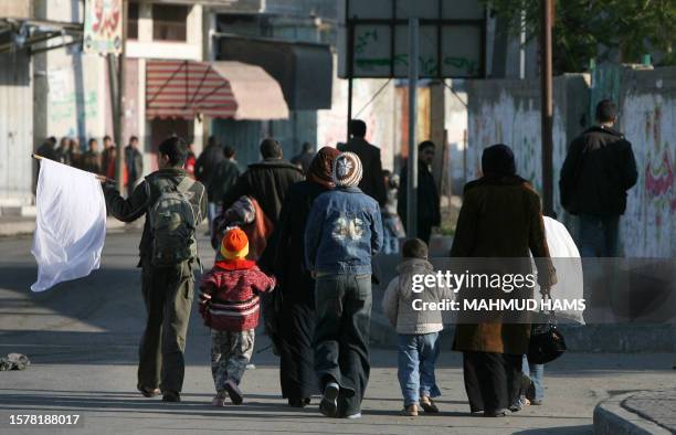 Man hold a white flag as Palestinian families flee the Zeitun district of Gaza City after Israeli strikes on January 12, 2009. Israeli troops clashed...