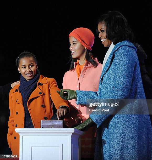 First lady Michelle Obama and their daughters Malia and Sasha Obama light the 90th National Christmas Tree during the Lighting Ceremony on the...