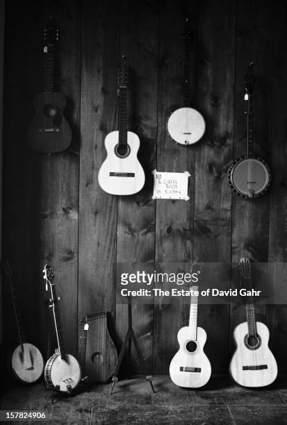 Handwritten sign reads 'No Bluegrass Bands On Sundays' posted beside folk music instruments including guitars, banjos, and an autoharp on display and...