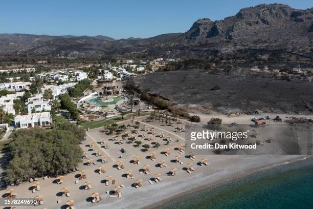 In an aerial view, an area ravaged by wildfire stands next to a hotel on the coastline on July 29, 2023 in Lardos, Rhodes, Greece. While A...
