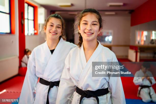 teenage girls smiling and looking at camera while learning taekwondo or karate - jiu-jitsu stock pictures, royalty-free photos & images