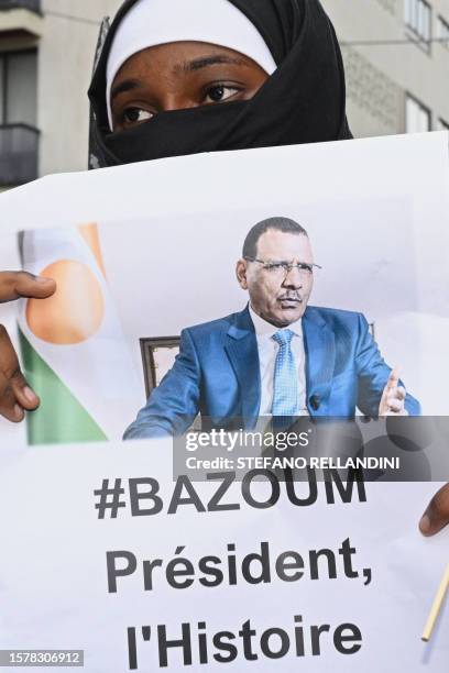 Woman holds the image of ousted Niger President Mohamed Bazoum who has been held by coup plotters with his family in his official Niamey residence...