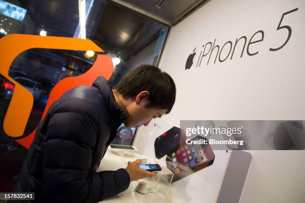 Customer examines an Apple Inc. IPhone 5 during a launch event organized by SK Telecom Co. In Seoul, South Korea, on Thursday, Dec. 6, 2012. The...