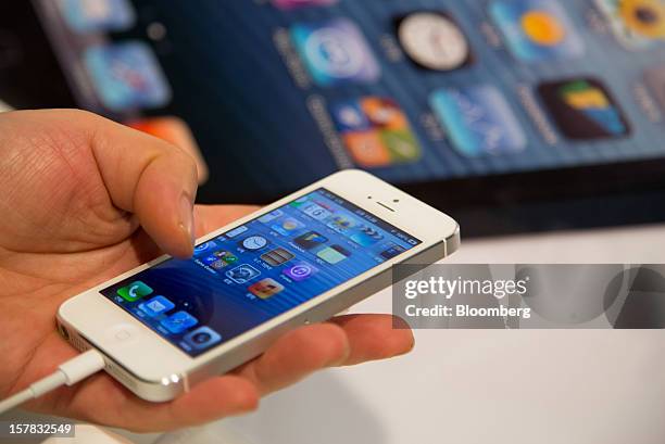 Customer examines an Apple Inc. IPhone 5 during a launch event organized by SK Telecom Co. In Seoul, South Korea, on Thursday, Dec. 6, 2012. The...