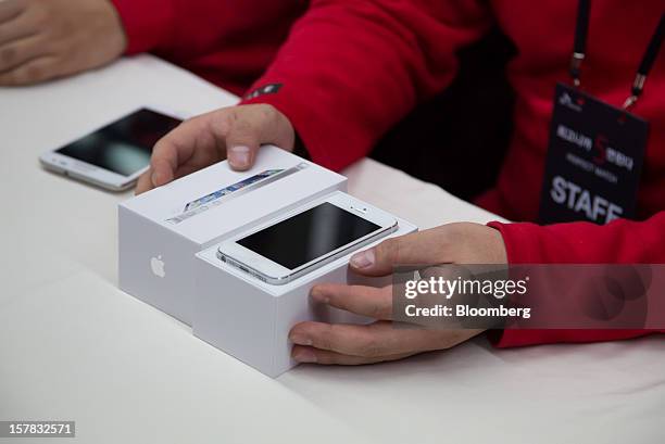 An SK Telecom Co. Employee unboxes an Apple Inc. IPhone 5 during a launch event in Seoul, South Korea, on Friday, Dec. 7, 2012. The iPhone 5 went on...