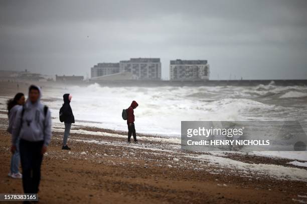 People walk along the beach in Brighton, southern England on August 5 as Storm Antoni brings rain and high winds to the UK.