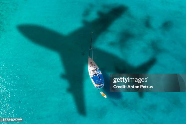 airplane over a yacht in turquoise water. greece - yachting stock pictures, royalty-free photos & images