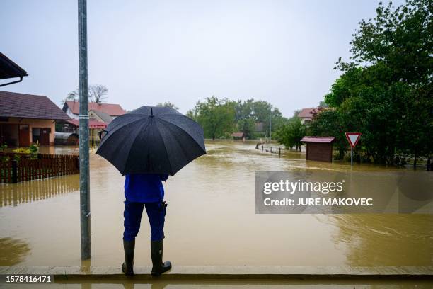 This photograph taken on August 5, 2023 shows a man looking at the houses flooded by the rising water of the river Krka, in the village of Loce,...