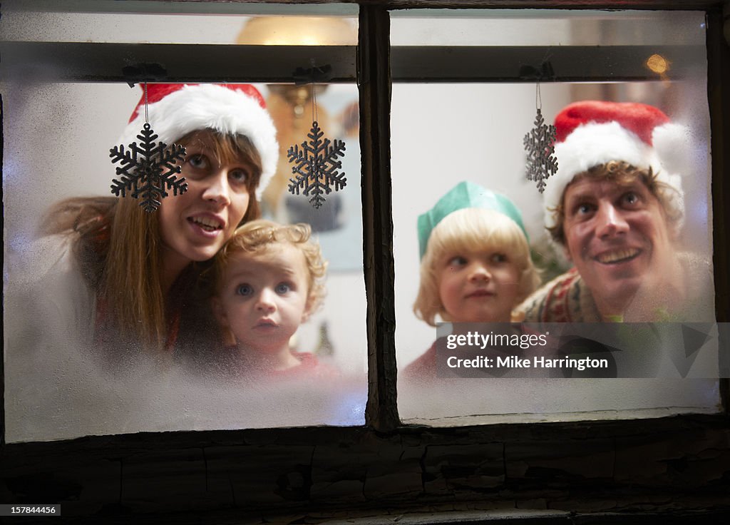 Family looking out of frosty windows at Christmas