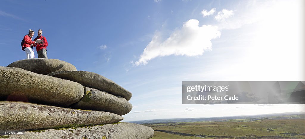 Couple looking at map, high on rock formation