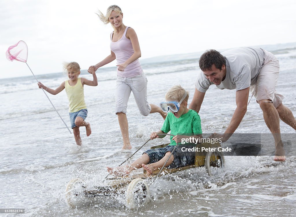 Family running on beach with hand made go-kart