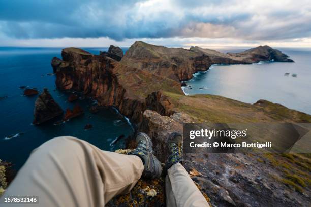 personal perspective of man sitting on top of a mountain admiring the sunrise, madeira, portugal - shoes top view stockfoto's en -beelden