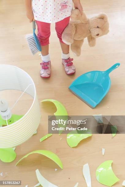 child stood by broken lamp with dustpan and teddy - broken lamp stock pictures, royalty-free photos & images