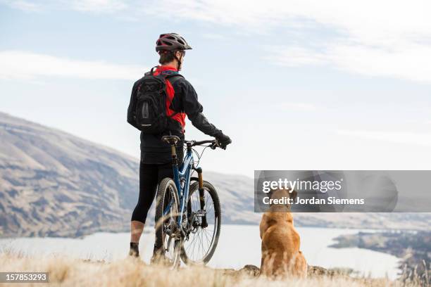 a man mountian biking with his dog. - casco de trabajo fotografías e imágenes de stock
