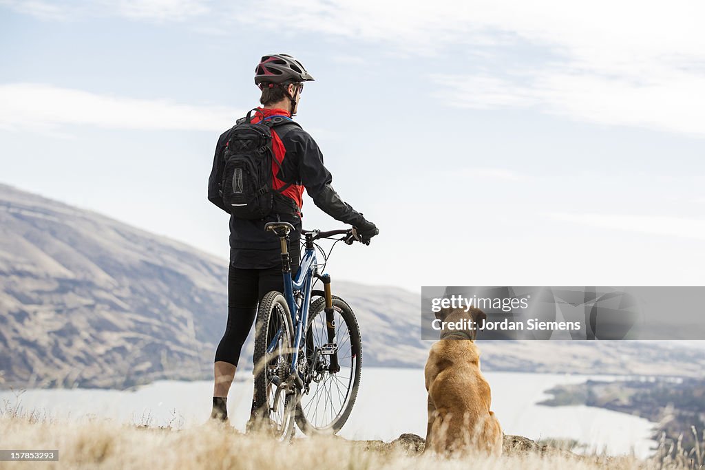 A man mountian biking with his dog.