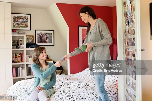 woman giving pocket money to her daughter - zakgeld stockfoto's en -beelden