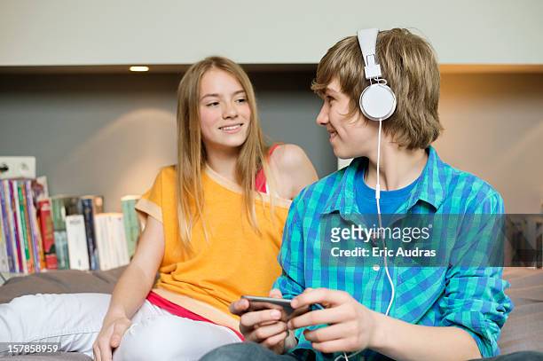 teenage boy listening to music on ipod with his sister at home - boy ipod bildbanksfoton och bilder