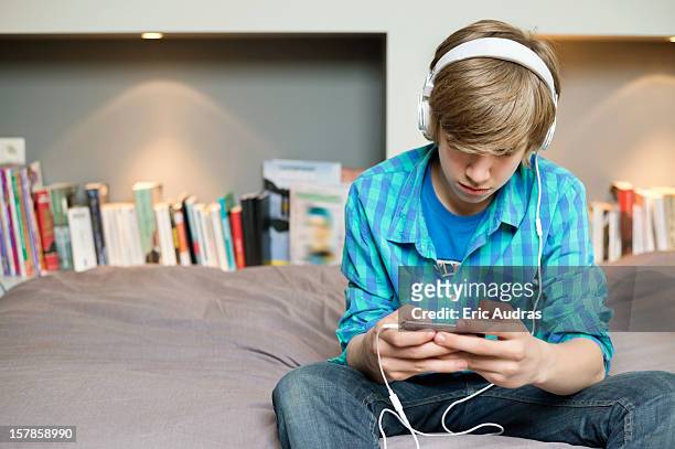 teenage boy listening to music on ipod at home - boy ipod bildbanksfoton och bilder