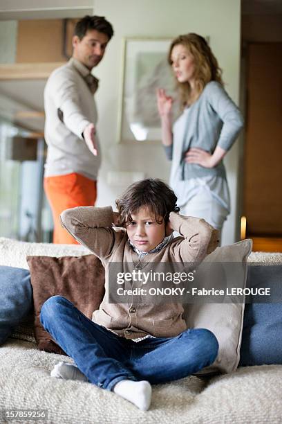 boy covering ears with hands while his parents arguing in the background - divorce kids stock pictures, royalty-free photos & images