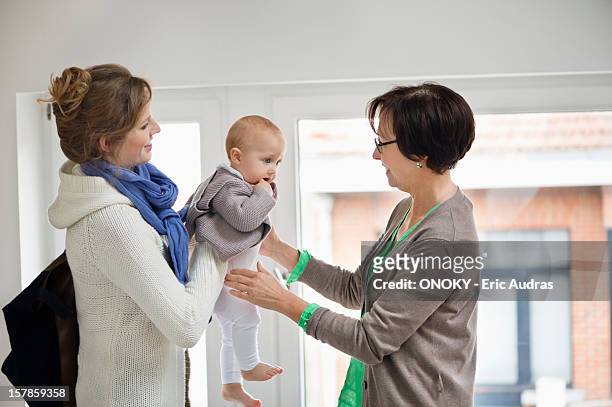 woman giving her daughter to nanny - nurse photos et images de collection