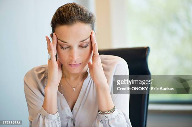 close-up of a businesswoman suffering from a headache in an office - hoofdpijn vrouw stockfoto's en -beelden