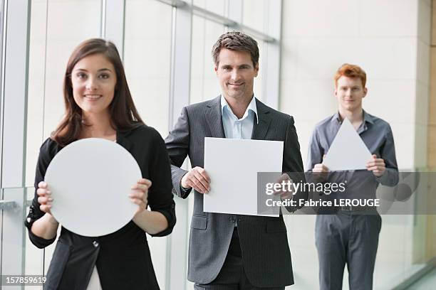 business executives holding geometrical shaped placards in an office - woman holding round sign stock pictures, royalty-free photos & images