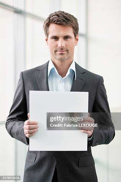 businessman holding a blank placard in an office - holding a sign stock-fotos und bilder