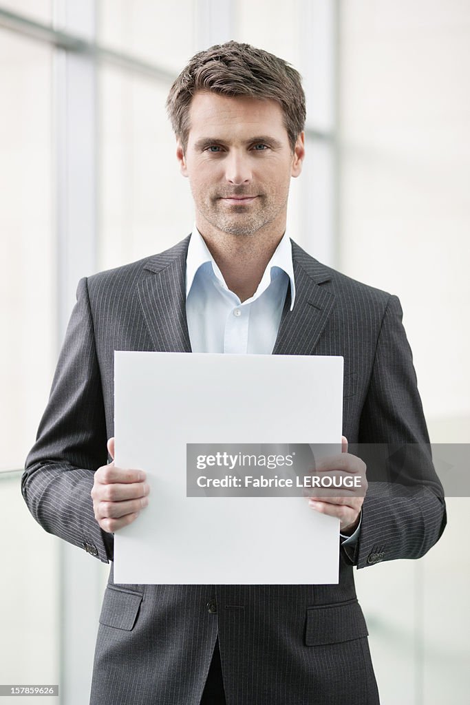 Businessman holding a blank placard in an office