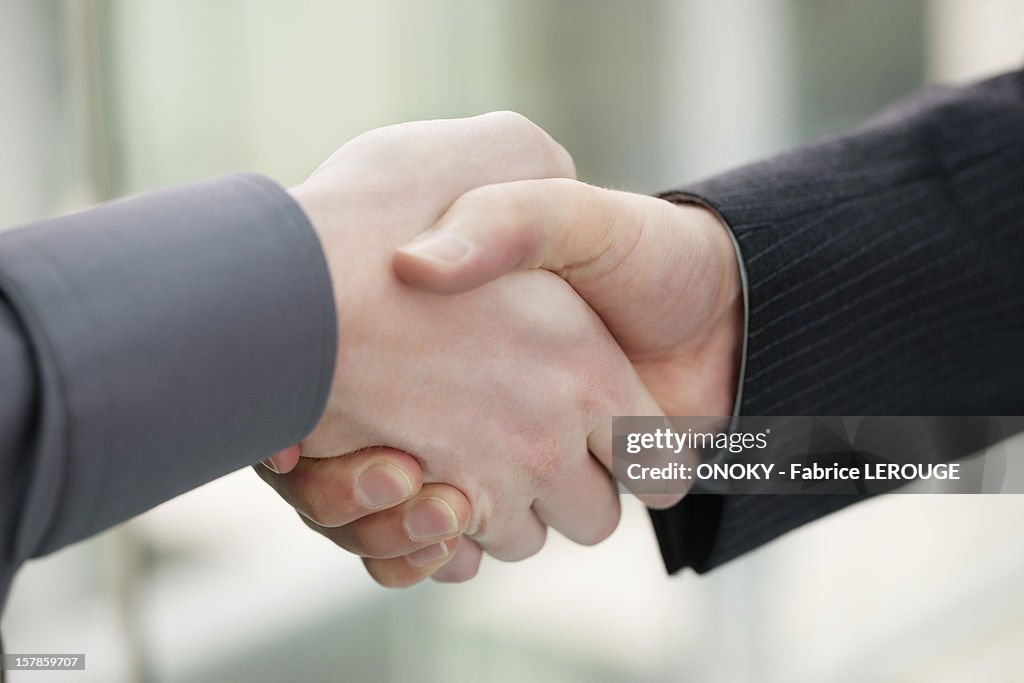 Close-up of businessmen shaking hands in an office