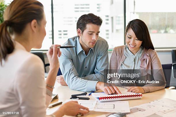 real estate agent discussing property documents to his clients - blank brochure stockfoto's en -beelden