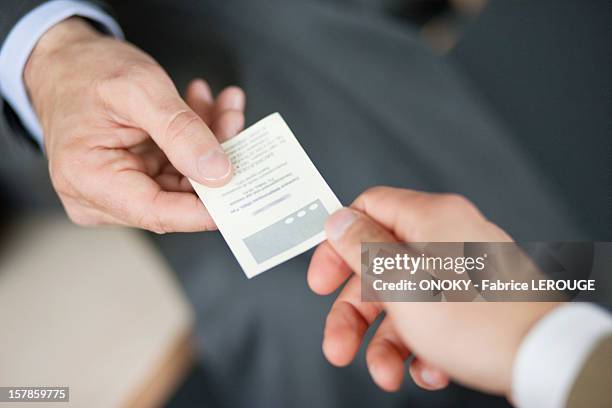 close-up of businessman giving card to another businessman - biglietto da visita foto e immagini stock