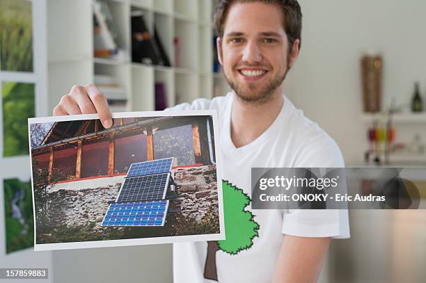 man showing an ecological poster of solar panel - one man only photos stock-fotos und bilder