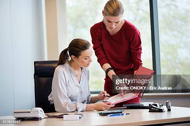 businesswoman signing documents with her secretary - secretary stock pictures, royalty-free photos & images