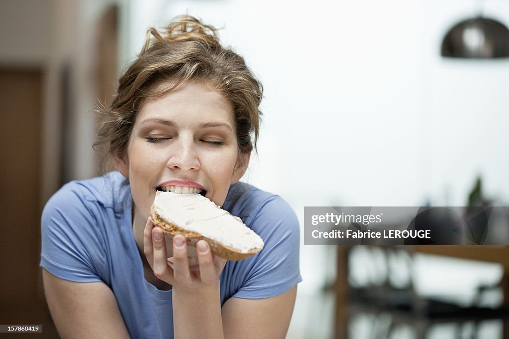 Close-up of a woman eating toast with cream spread on it