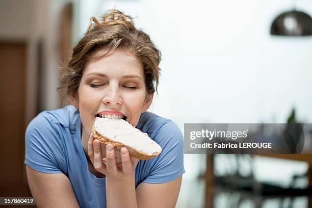 close-up of a woman eating toast with cream spread on it - cream cheese stock pictures, royalty-free photos & images