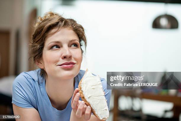 close-up of a woman eating toast with cream spread on it - blond women happy eating stock pictures, royalty-free photos & images